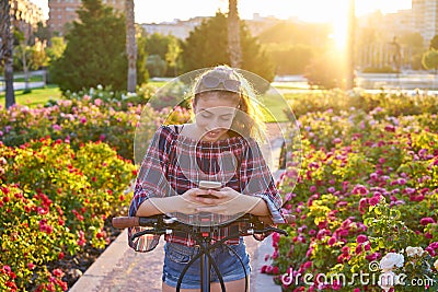 Girl bicycle playing with smartphone in park Stock Photo