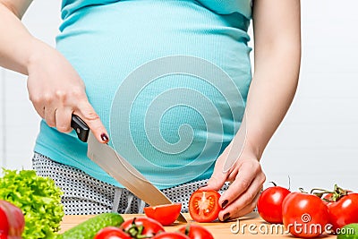 Girl with a big belly prepares a salad of vegetables Stock Photo