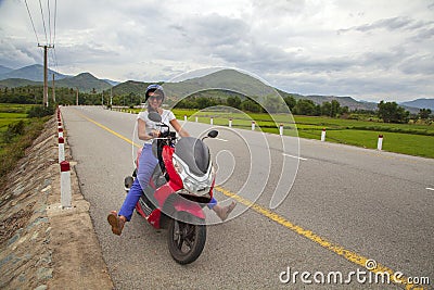 Girl biker riding a scooter in the mountains of Vietnam, Woman in blue helmet riding scooter motorbike, Female traveler riding a Stock Photo