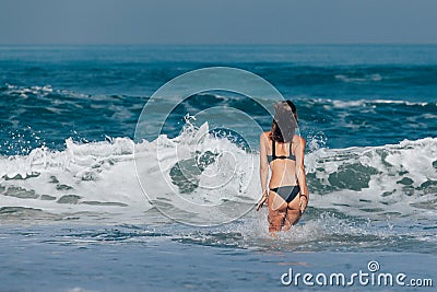 Girl in black swimsuit going into the sea Stock Photo