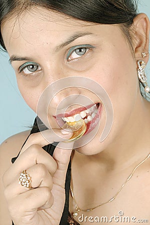 Girl biting gold coin Stock Photo