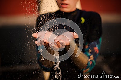 Girl in the black diving suit standing under the shower place hands under water Stock Photo