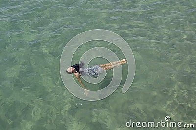 A Girl with black hair laying in the ocean Stock Photo