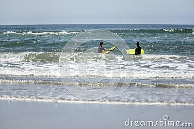 Girl in black overalls swim on the boards in the Pacific Ocean Editorial Stock Photo