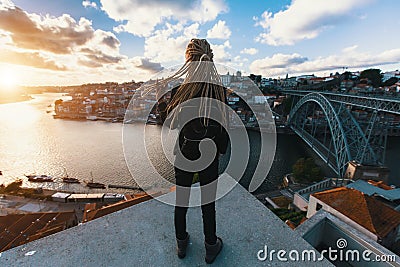 Girl with blonde dreadlocks standing on the background of the bridge Dom Luis I over Douro river, Porto Stock Photo