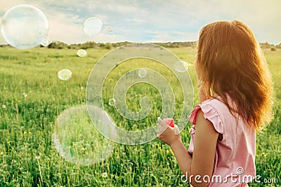 Girl blowing soap bubbles in summer at sunny day Stock Photo