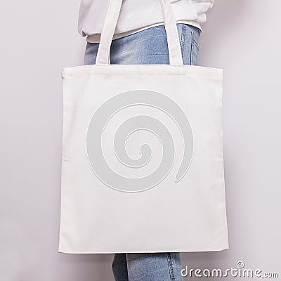 Girl in blue jeans holds blank cotton eco tote bag, design mockup. Handmade shopping bag for girls Stock Photo