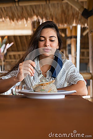 Girl in a blue mask sits in a cafe and eats fried rice Stock Photo