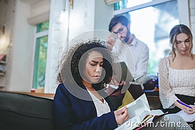 Girl with a book, girlfriend writing in notebooks, boyfriend with laptop. Stock Photo