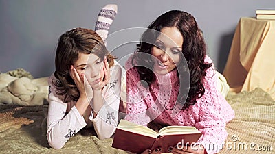 Girl bored with storybook her mother reading before bedtime, togetherness Stock Photo