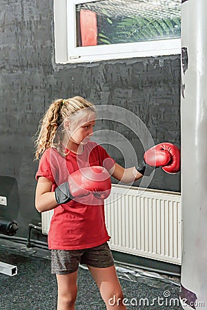 A girl in boxing gloves hits a punching bag in the gym Stock Photo