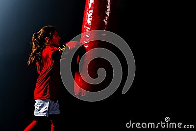 A girl in boxing gloves hits a punching bag Stock Photo