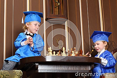 Girl and boy in blue suits play chess Stock Photo