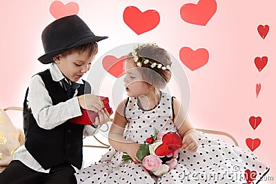 Girl and boy sitting together like lady and gentleman giving present Stock Photo