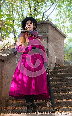 Girl in a bright crimson coat goes the steps. Stock Photo