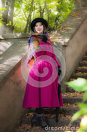 Girl in a bright crimson coat goes the steps. Stock Photo