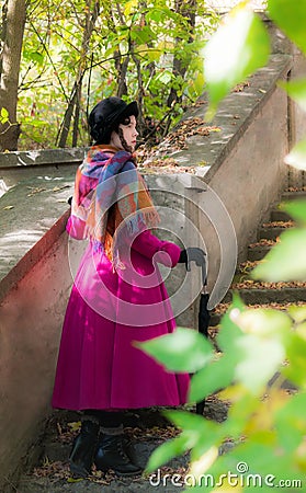 Girl in a bright crimson coat goes the steps. Stock Photo