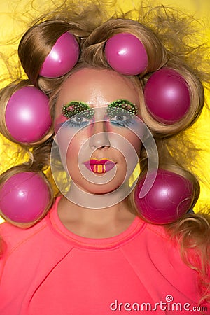 Girl with bright makeup and hair balls on yellow background Stock Photo