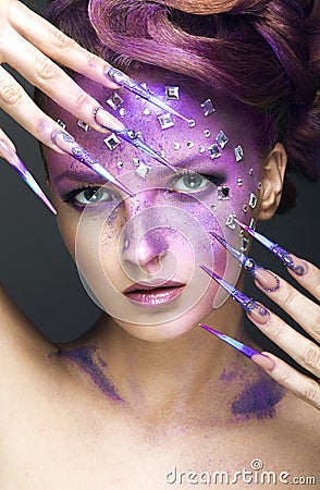 Girl with bright purple creative makeup with crystals and long nails. Beauty face. Stock Photo