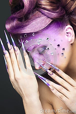 Girl with bright purple creative makeup with crystals and long nails. Beauty face. Stock Photo