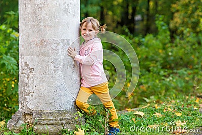 .A girl with a broken arm stands near a column in an old park Stock Photo