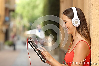 Girl browsing a tablet and listening with headphones Stock Photo