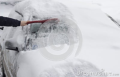 The girl brushes the car from the snow with a brush ice Stock Photo