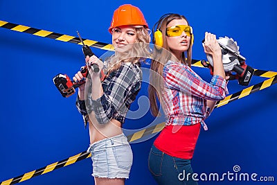 Girl builder in the construction helmet and goggles with a construction tool on a blue background Stock Photo