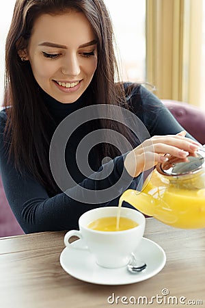 Girl in cafe drinking sea buckthorn tea pouring it Stock Photo