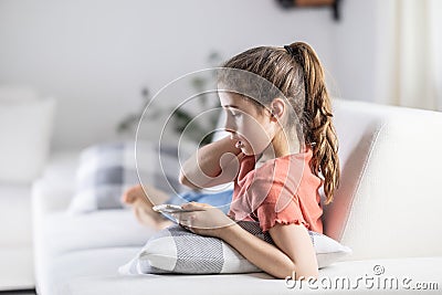 Girl captured by online content on her phone focuses on her phone instead of what is around her at home Stock Photo