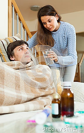 Girl caring for sick husband in living room Stock Photo