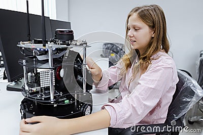 Girl Caucasoid education electronic robotic arm on table at class room. Stock Photo