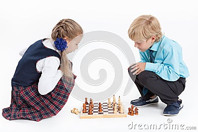 Girl checkmates boy, schoolchildren in uniform playing chess, isolated white background Stock Photo