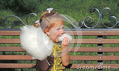 Girl child eating cotton candy in the park for a walk. Stock Photo