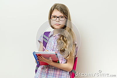 Girl child elementary school student wearing glasses with a backpack, notebook. Bright school wall background Stock Photo