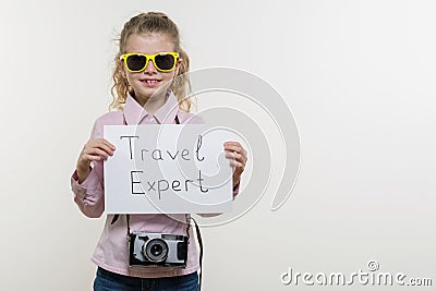 Girl child holding piece of paper with a word TRAVEL EXPERT. White bakgrounde, copy space Stock Photo