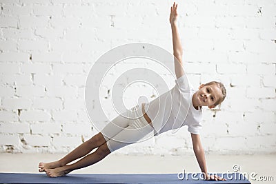 Girl child in Vasisthasana pose, white studio background Stock Photo