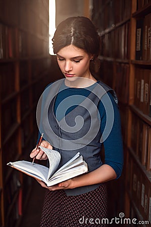 Girl choose book with notebook in her hands. Stock Photo
