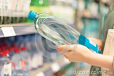 Girl choosing bottle of drinking water in grocery section of supermarket. Copy space. Water balance and body hydration. Healthy Stock Photo