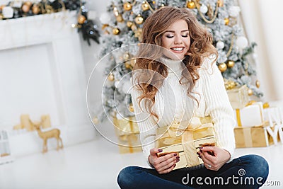 Girl with Christmas gift near beautiful dressed Christmas tree Stock Photo