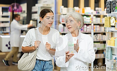 Girl client consults with mature pharmacist which medicinal ointment to buy Stock Photo