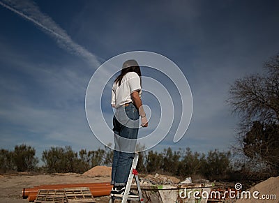 Girl climb a ladder in an industrial outside Stock Photo