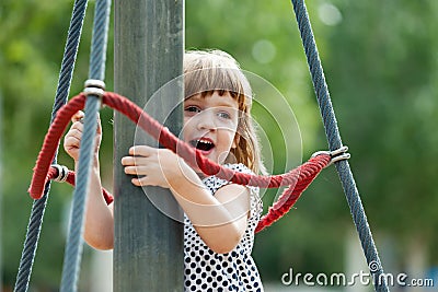 Girl climbing at ropes on playground Stock Photo