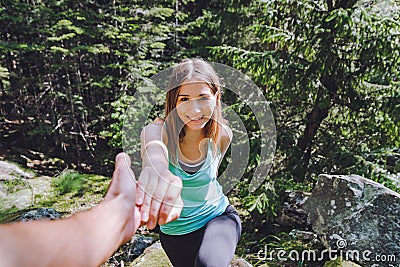 Girl climbs on rock, partner pulls out hand for assistance Stock Photo