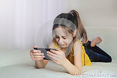 The girl closed her eyes afraid to look at the phone while lying on a sofa at home Stock Photo