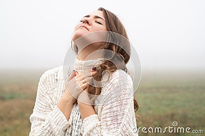 Girl closed her eyes, praying in a field during beautiful fog. Hands folded in prayer concept for faith Stock Photo