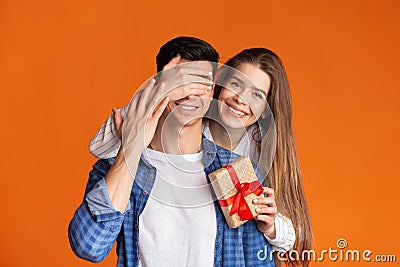 Girl closes eyes to guy and gives him gift Stock Photo