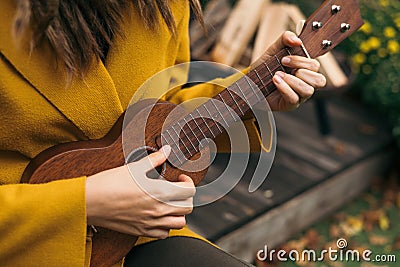 Girl closeup playing an acoustic instrument ukulele in autumn on the terrace Stock Photo