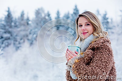 Girl in coat with cup of drink in a snow forest Stock Photo