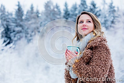 Girl in coat with cup of drink in a snow forest Stock Photo